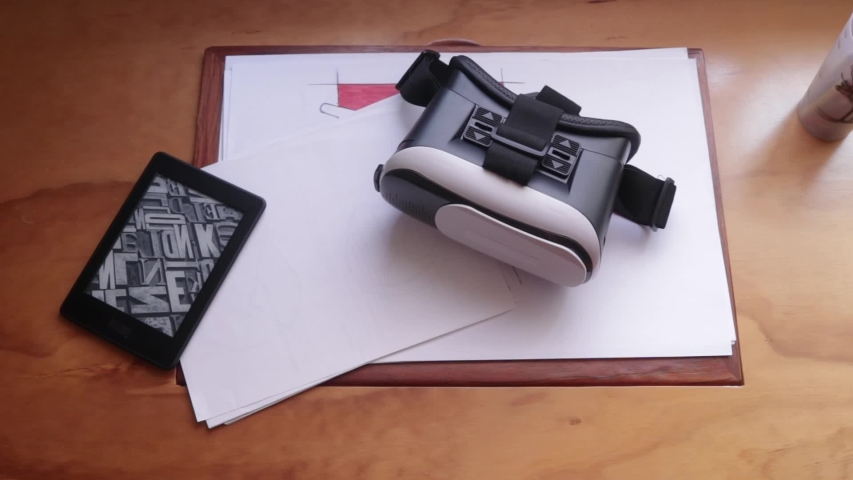 Top view. Male hands puts aside a vr headset from wooden desk and take the ebook reader. Virtual reality for home. Virtual reality gadget to use with a mobile phone. 3d experience with a vr headset