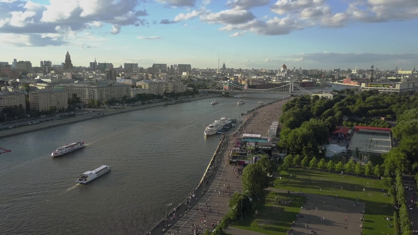 A wide panoramic aerial view of Moskva river in Moscow center with its architecture on the far bank and walking citizens on the near bank