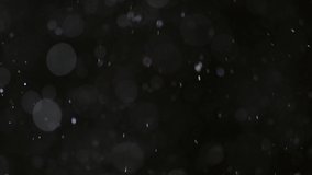 Abstract particles floating, motion, random flickering. Dust sparkles on black background. Real Glittering flying particles Bokeh. Holiday backdrop. For screen mode. Slow motion 4K UHD