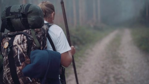Way of Saint James pilgrim backpacker female going by the path through Eucalyptus forest  back view slow motion footage.