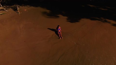 Aerial footage of a model in bikini enjoying the breaking of the waves at the shoreline