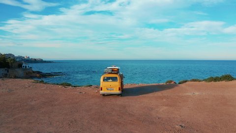 California, United States, JULY 20TH, 2019: Aerial view. Yellow VW bus van on a parking lot on a rock near the sea.