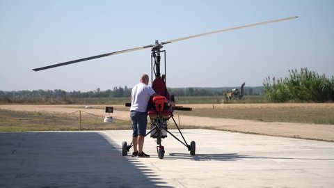 Sintra / Portugal - 20.05.2019: Adult male person start engine of homemade aircraft autogyro on rural airfield before flight. DIY hobby aviation on ultralight gyrocopter