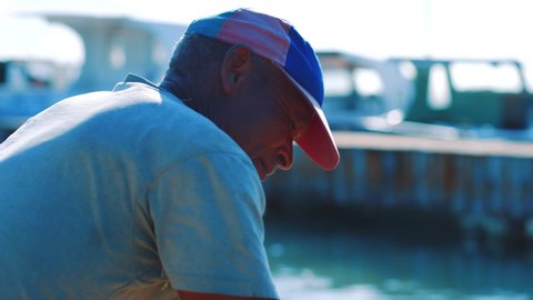 Bonaire, Venezuela - 01 17 2019: Slow motion shot of a male Caribbean fishermen cleaning and filleting a freshly caught Barracuda by the water