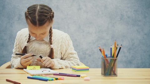Nice schoolgirl has a good time colouring a picture.