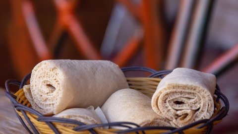 Zoom out on still image of rolls of Injera in a serving bowl.  Injera is a sourdough flatbread made from teff flour.  It is a staple food of Ethiopia, Eritrea, Somalia and Djibouti