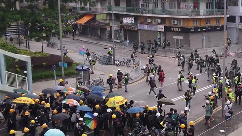 HONG KONG - JULY 27 2019: Police throws a tear gas to disperse protesters and hits an umbrella then explodes into tear smoke during the anti-extradition law protest in Hong Kong