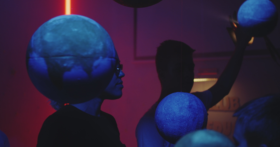 Medium shot of a female teacher explaining astronomy to students with suspended planet models