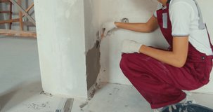 Closeup of repairman hand plastering a wall with putty knife or spatula. Young woman in construction uniform. Girl making repairs in the house. 4K slow motion raw video footage 60 fps