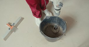 Mixing plaster solution in a bucket, using an electric drill. Girl making repairs in the house. 4K slow motion raw video footage 60 fps