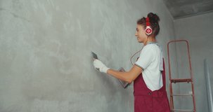 Repair and renovation at home. New interior design. Woman worker scrubbing wall with sandpaper and prepare surface for painting. Girl making repairs in house. 4K slow motion raw video footage 60 fps