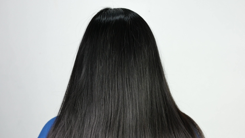 Rear of Asian young woman standing isolated at grey background and brushing her long hair | Shutterstock HD Video #1034097287