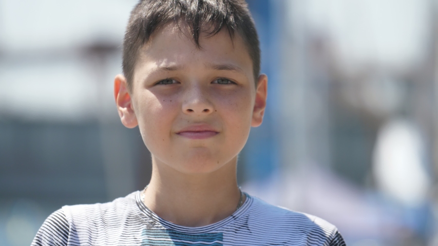Wonderful bokeh portrait of small brunette boy with short haircut in T-shirt standing in the Dnipro quay with yachts and boats and smiling in summer in slow motion | Shutterstock HD Video #1034097935