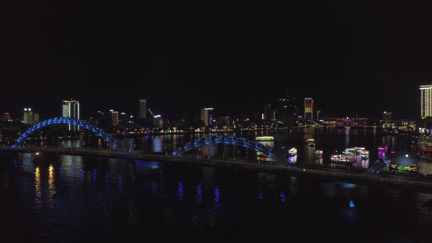 beautiful asian Dragon bridge in Da Nang, Vietnam at night, road traffic, river, boats and ships