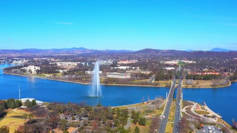 Dolly aerial view of Lake Burley Griffin with the Captain James Cook Memorial Jet, the National Library of Australia behind the fountain and Commonwealth Bridge in Canberra, the capital of Australia