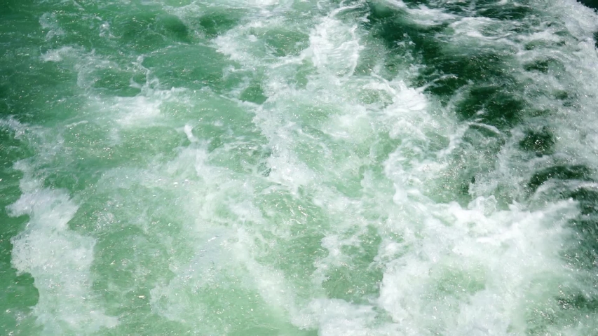 Waves of the sea foam and shallow ripples near the ship.
