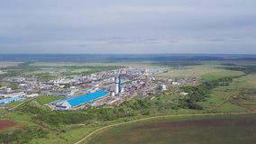 Breathtaking aerial view of the industrial area with factory surrounded by green meadows and trees. Clip. Agricultural area fields with juicy grass and trees near recycling plant.