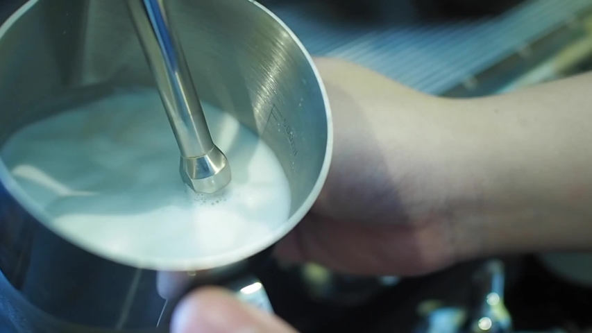 Barista streaming a milk to prepare latte art.