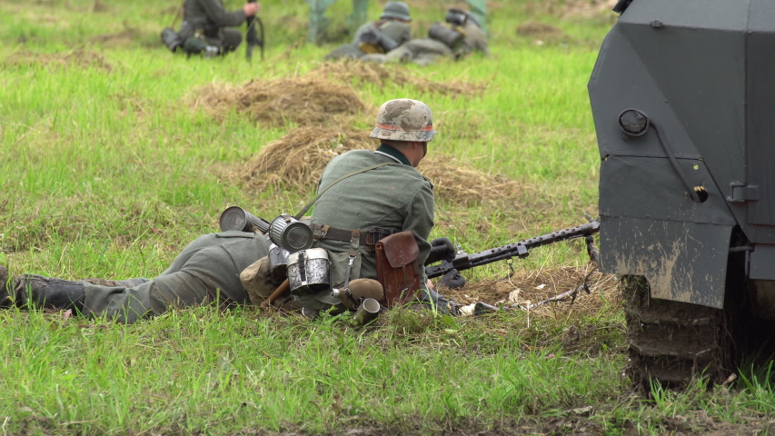 Machine gunners. Soldiers shoot a machine gun at the enemy, one helps to load the weapon and the other is firing