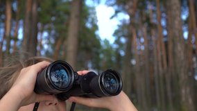 Closeup portrait of cute curious kid exploring nature using old vintage binoculars. Beautiful blue sky, river and nature reflected in glass of lenses. Real time 4k video footage.