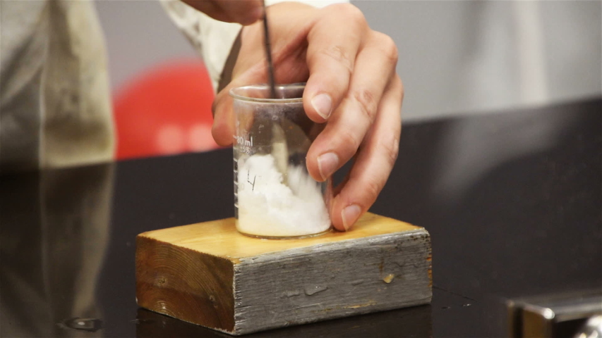 A hand is seen stirring different chemicals in a beaker Royalty-Free Stock Footage #1034121635