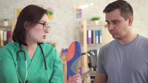 Orthopedic doctor tells the man about orthopedic insoles close up