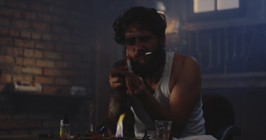 Medium shot of a drug addict heating drug in a spoon over flame then filling a syringe with it