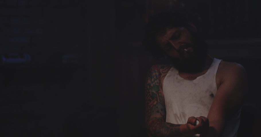 Medium shot of a young man being overwhelmed with pain after injecting drug