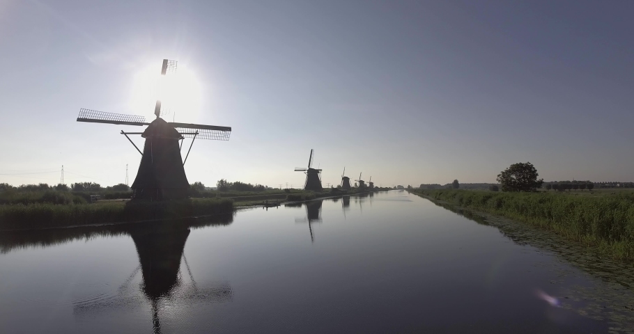 A drone shot panning left, around Dutch Windmills during sunrise