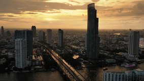 Stunning view of Bangkok at sunset time. The orange sky is wrapping Sapham Taksim bridge and the Chao Phraya river. Thon Buri.