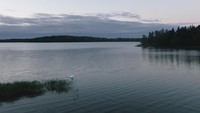 Slow Motion. Drone flying over water. Man controlling quadcopter drone near lake.
