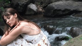 Very beautiful girl model sitting in the jungle near the water.
