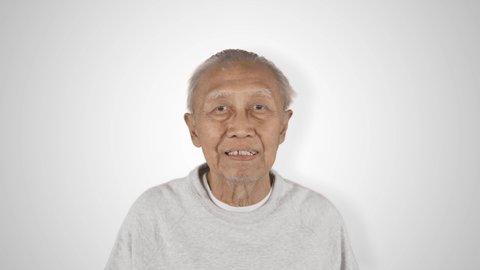 Happy elderly man smiling and showing thumbs up in the studio. Shot in 4k resolution, isolated on white background
