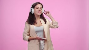 beautiful smiling girl in headphones with smartphone listening music and dancing Isolated On pink