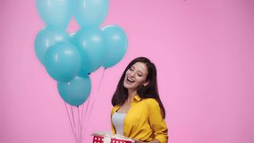 beautiful girl with balloons and gift looking at camera and smiling Isolated On pink