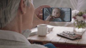 mature woman having video chat using smartphone grandmother waving at baby enjoying chatting to grandchild on mobile phone screen 4k footage