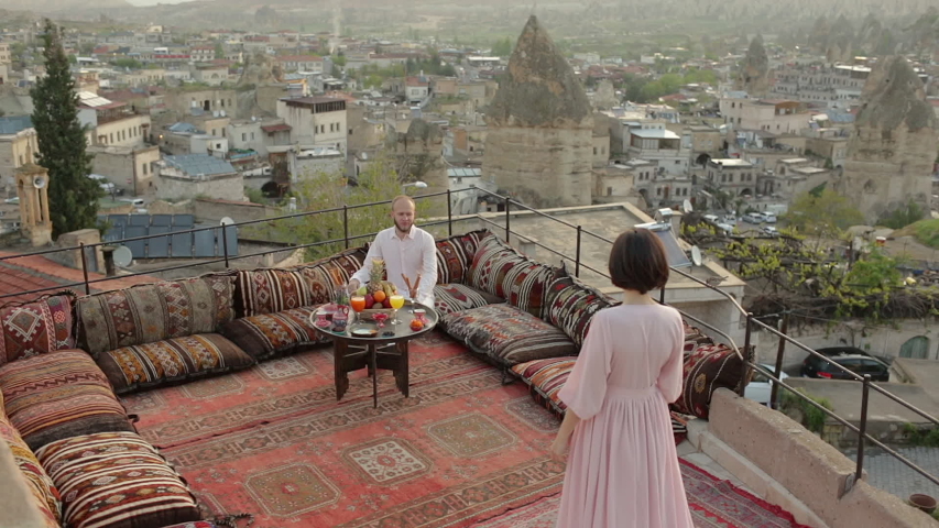 Woman and men sitting on the top of roof and enjoys the morning view on Goreme park, Cappadocia