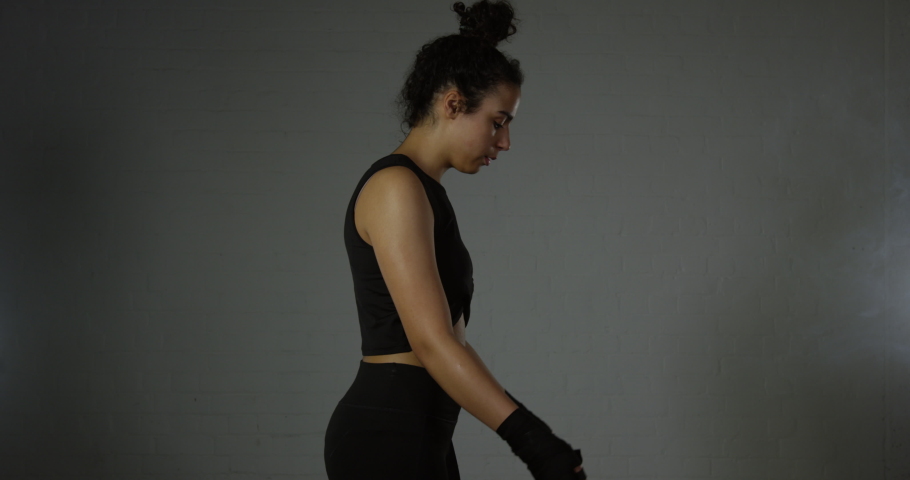 Female Sporty Woman Skipping At Gym Wearing Black Exercise Clothes And Wrapped Hands Warming Up To Work Out