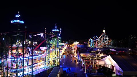 Düsseldorf, Germany - JULY 2019: Aerial top view of amusement park, carnival  or festival called Rheinkirmes, with crowd of visitors and colourful illuminating of amusement rides during night time.