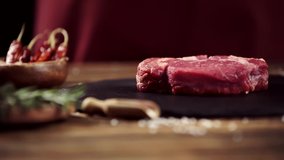 selective focus of falling salt on raw meat steak on table with ingredients
