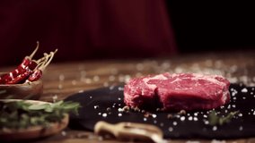 Cropped view of man rubbing raw meat steak with rosemary near ingredients on table