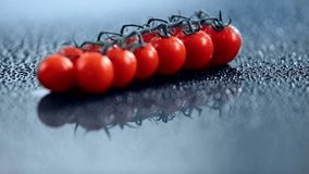 selective focus of fresh cherry tomatoes on branch with sprinkling water