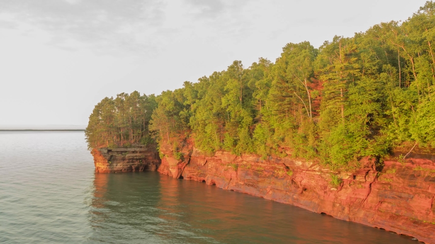 A Wide Timelapse Shot of Pink Clouds over a Cavernous Cliffside along the South Shore of Lake Superior on a Beautiful Summer Evening 4K UHD