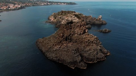 Aerial orbiting view of the faraglioni and the fishing village of Acitrezza on the East coast of Sicily