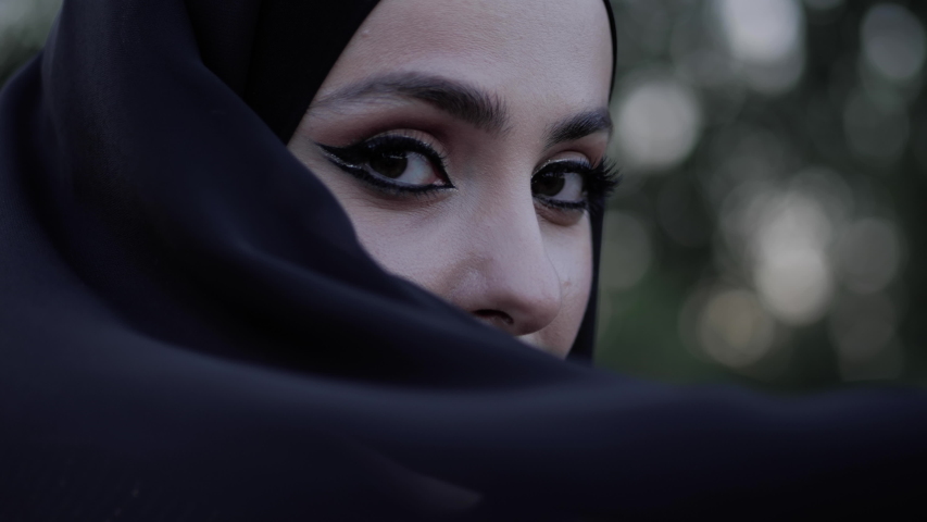 gorgeous arabian lady expressive eyes behind long black hijab on windy day extreme close view slow motion Royalty-Free Stock Footage #1034183300