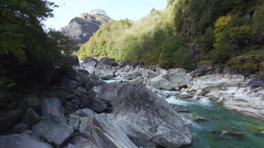 aerial view of Crystal wild turquoise mountain river Verzasca valley in Swiss alps. Close fly by over massive stones in River at canton of Ticino, switzerland