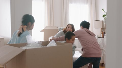 happy asian family moving into new home owners with children helping parents move into house carrying boxes enjoying teamwork together with kids real estate property investment 4k footage