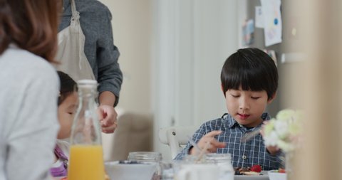 happy Japanese family eating pancakes for breakfast children enjoying healthy homemade meal with parents on weekend morning in kitchen 4k footage
