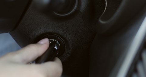 A woman's hand inserts the ignition key into the lock. Close-up.