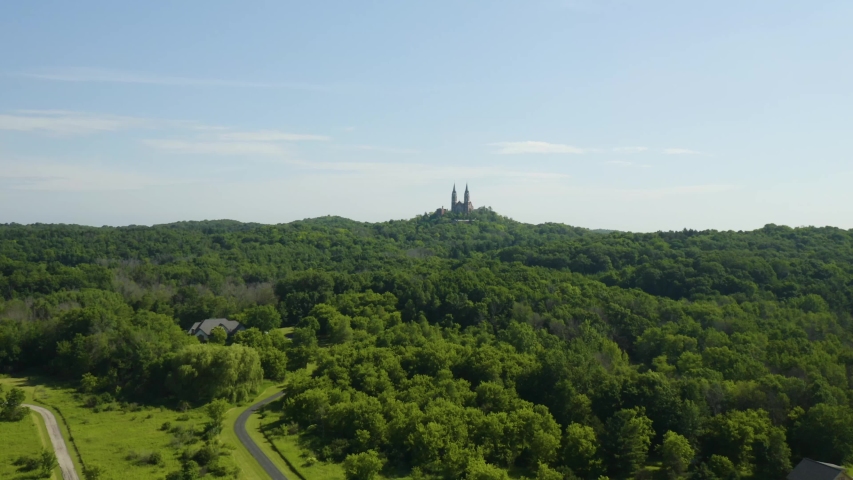 Aerial panoramic view flying over densely forested land towards Holy Hill Basilica and the National Shrine of Mary, Wisconsin, USA.